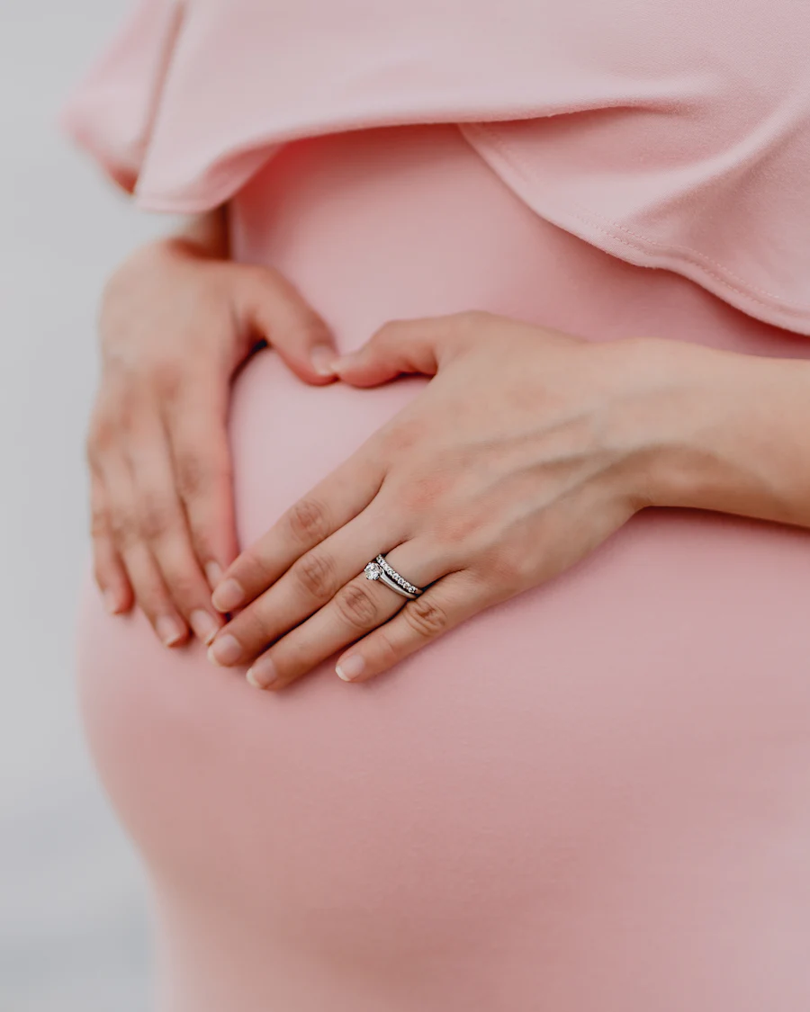 Gestante com as mãos formando um coração sobre a barriga