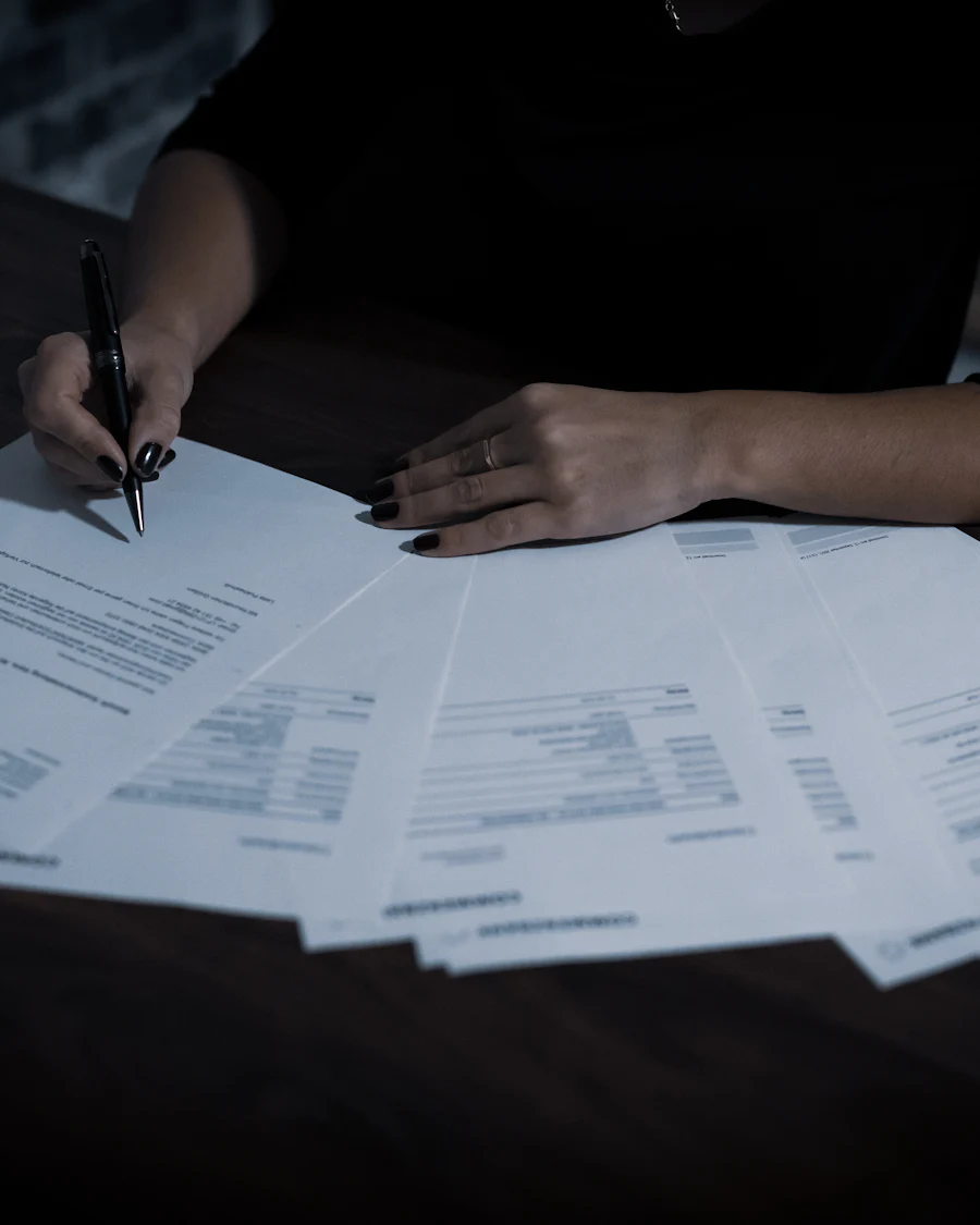 Mãos de uma pessoa analisando documentos e formulários sobre a mesa